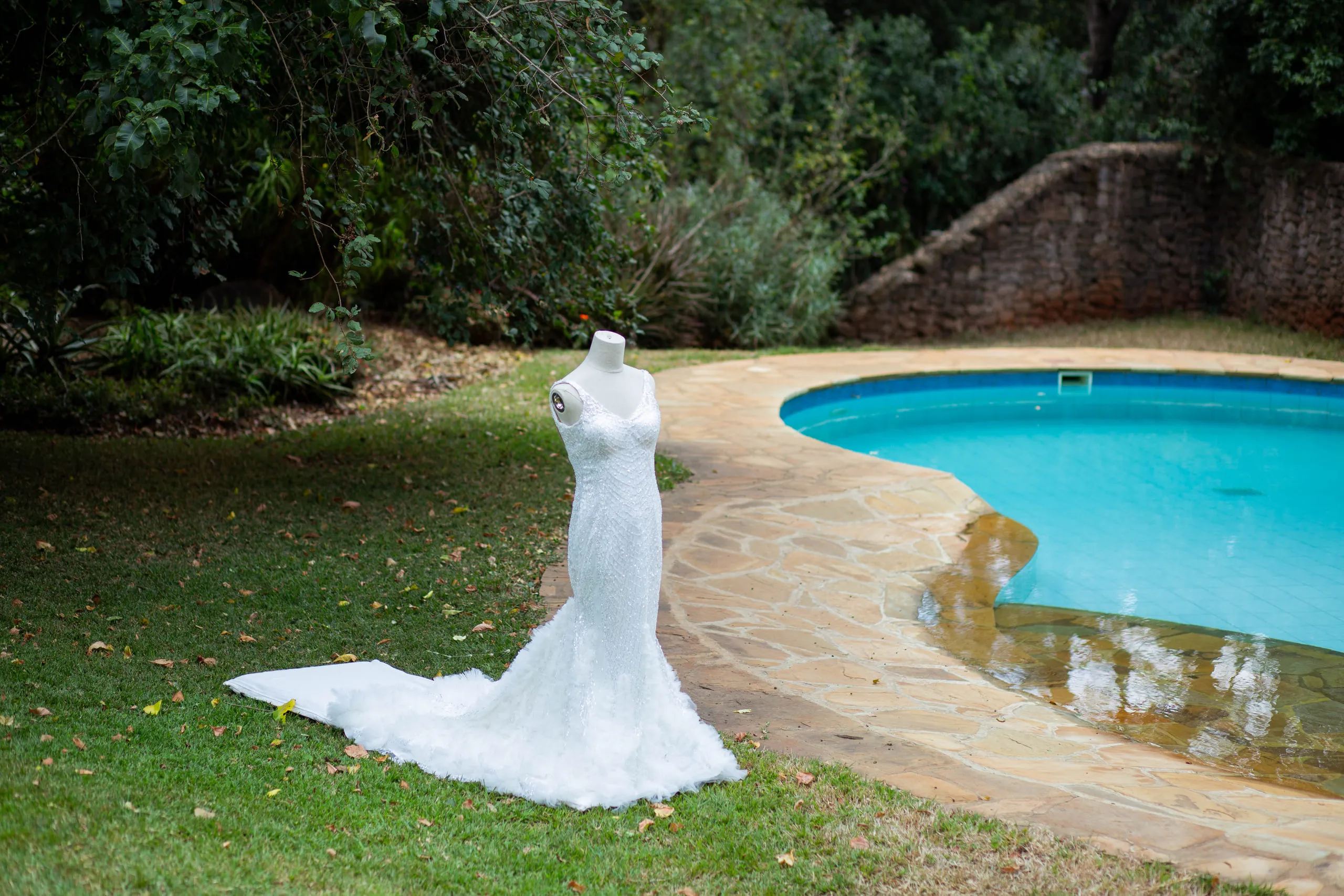 Wedding gown on a stand beside a curved pool