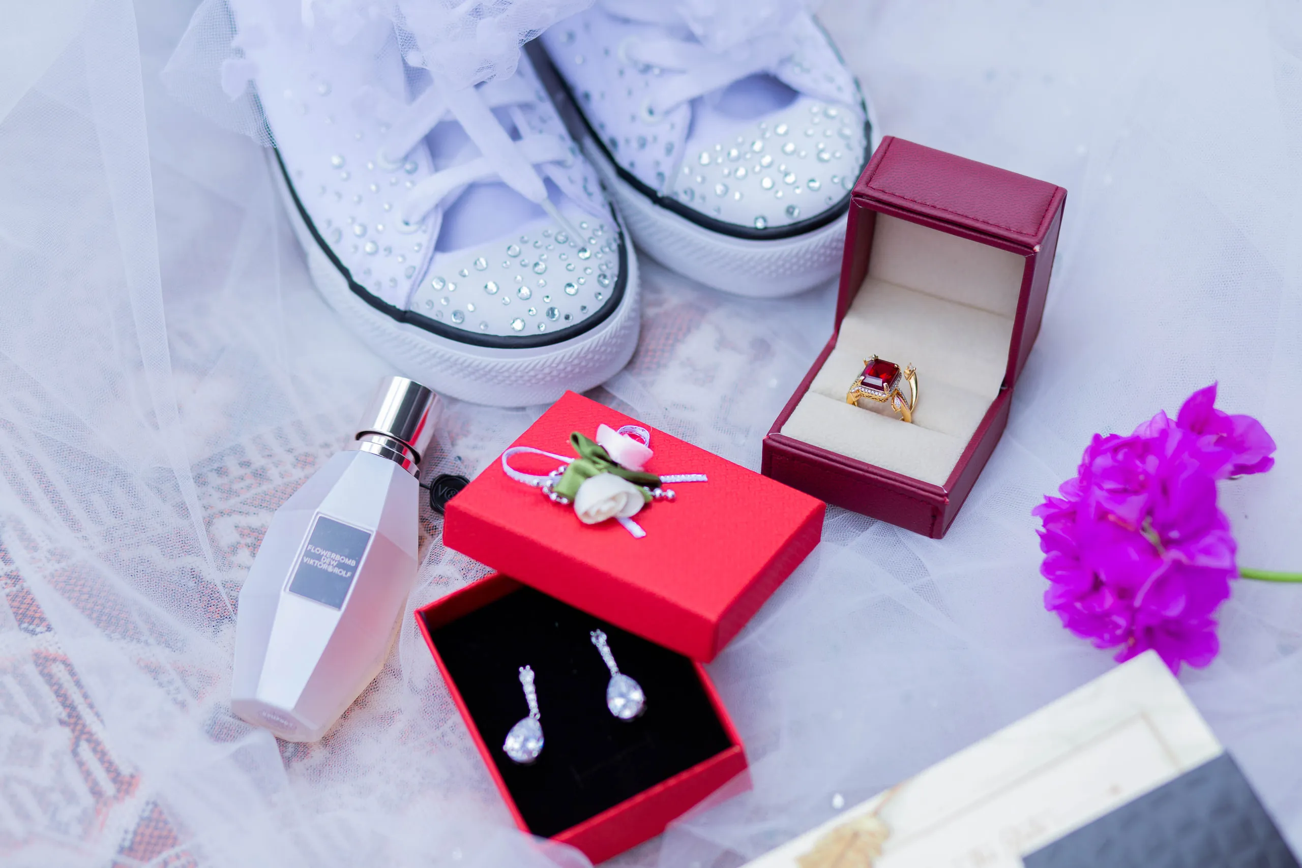 Jewelled sneakers, ring boxes, earrings and perfume on tulle