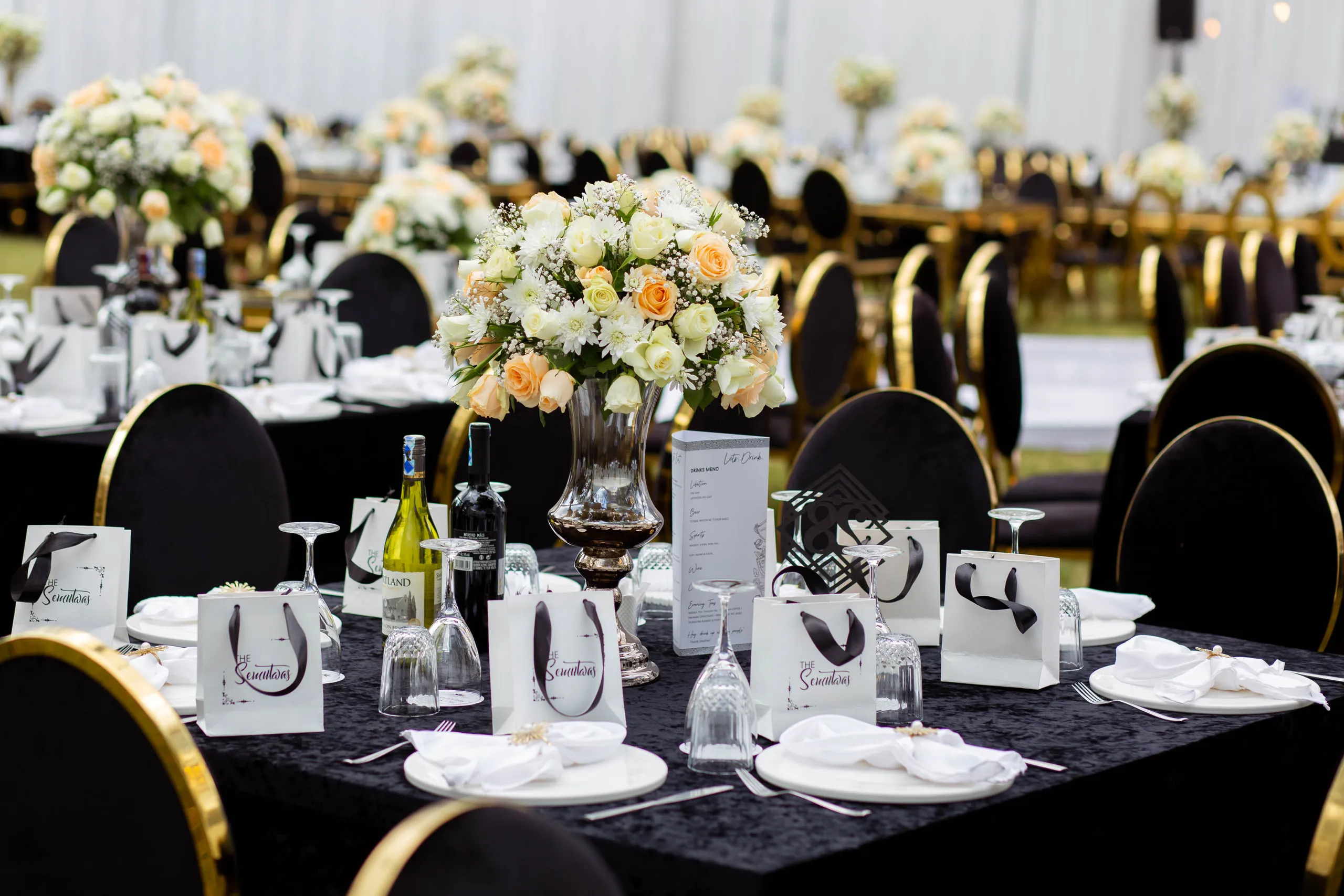 Reception tables in black and gold with peach roses