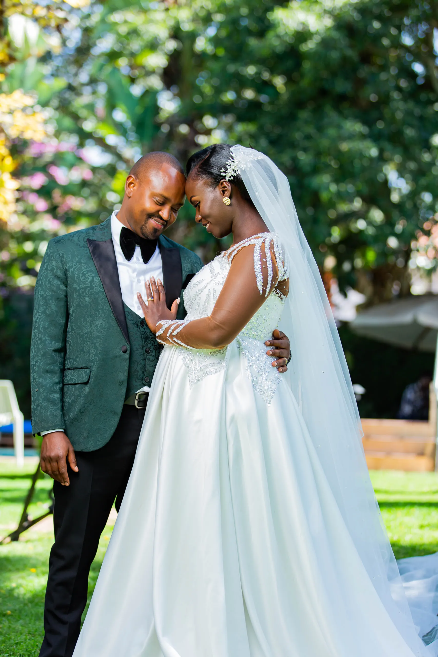 Bride and groom forehead to forehead in a sunny garden