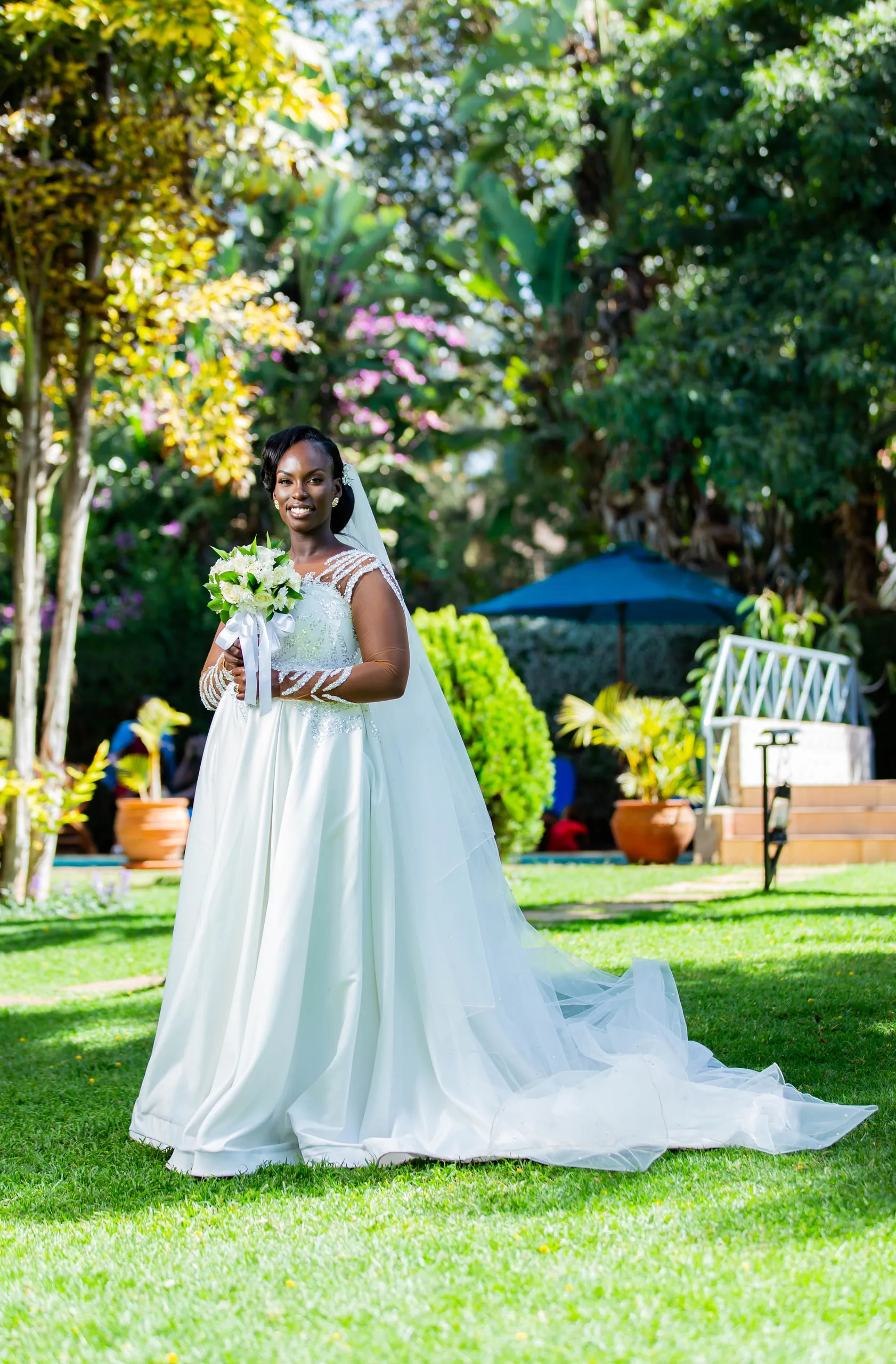 Bride alone on a lawn with her long train spread behind her