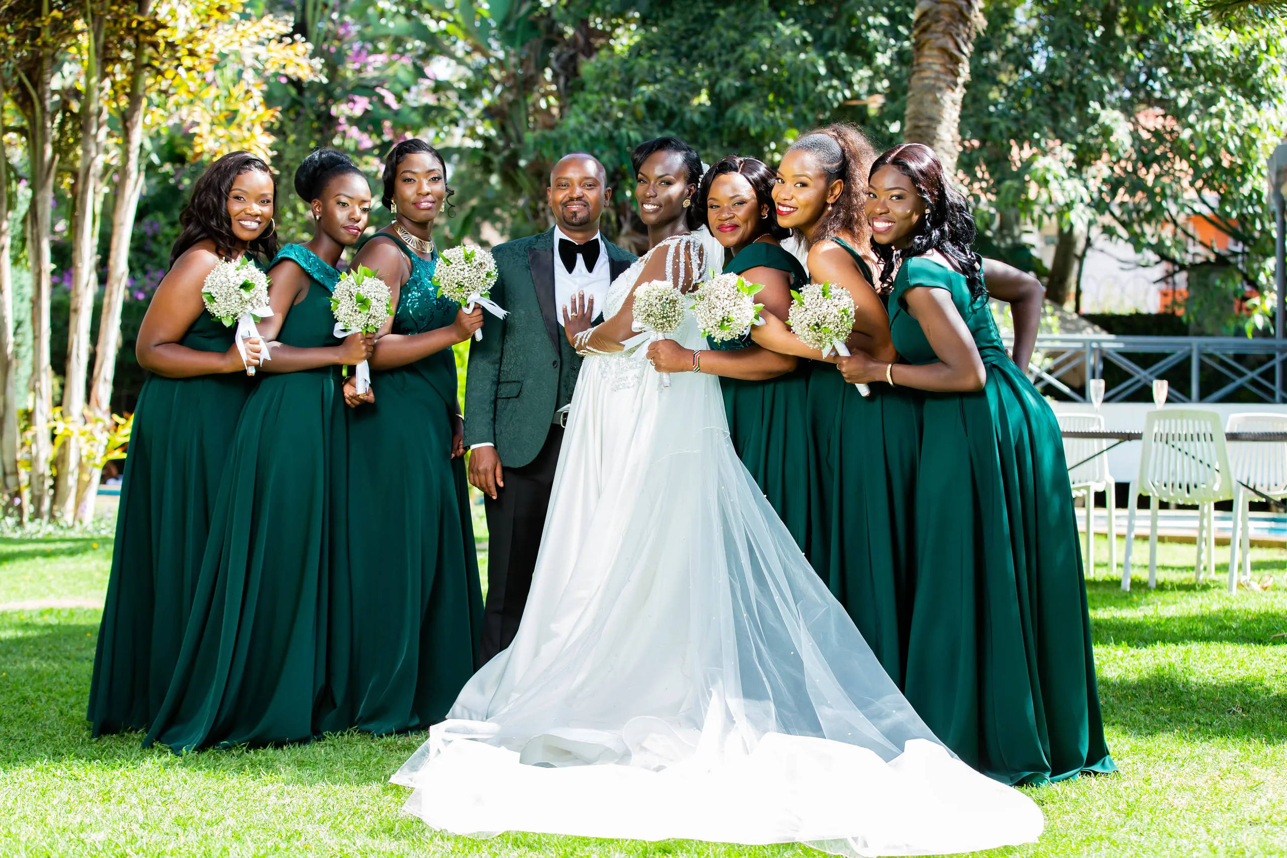 Bride and groom hugging among the bridesmaids in emerald