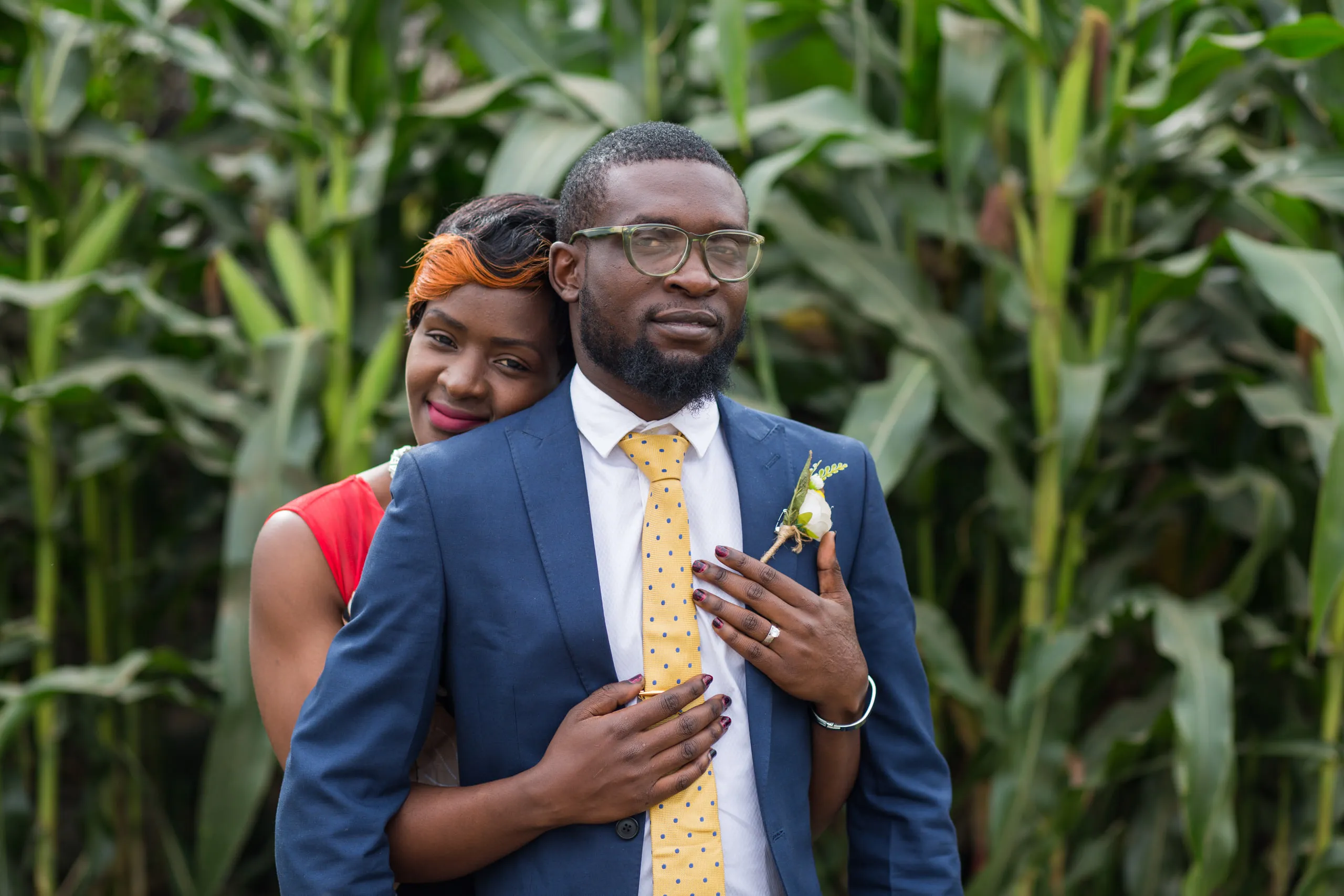 Couple standing in a maize field, he in a blue suit