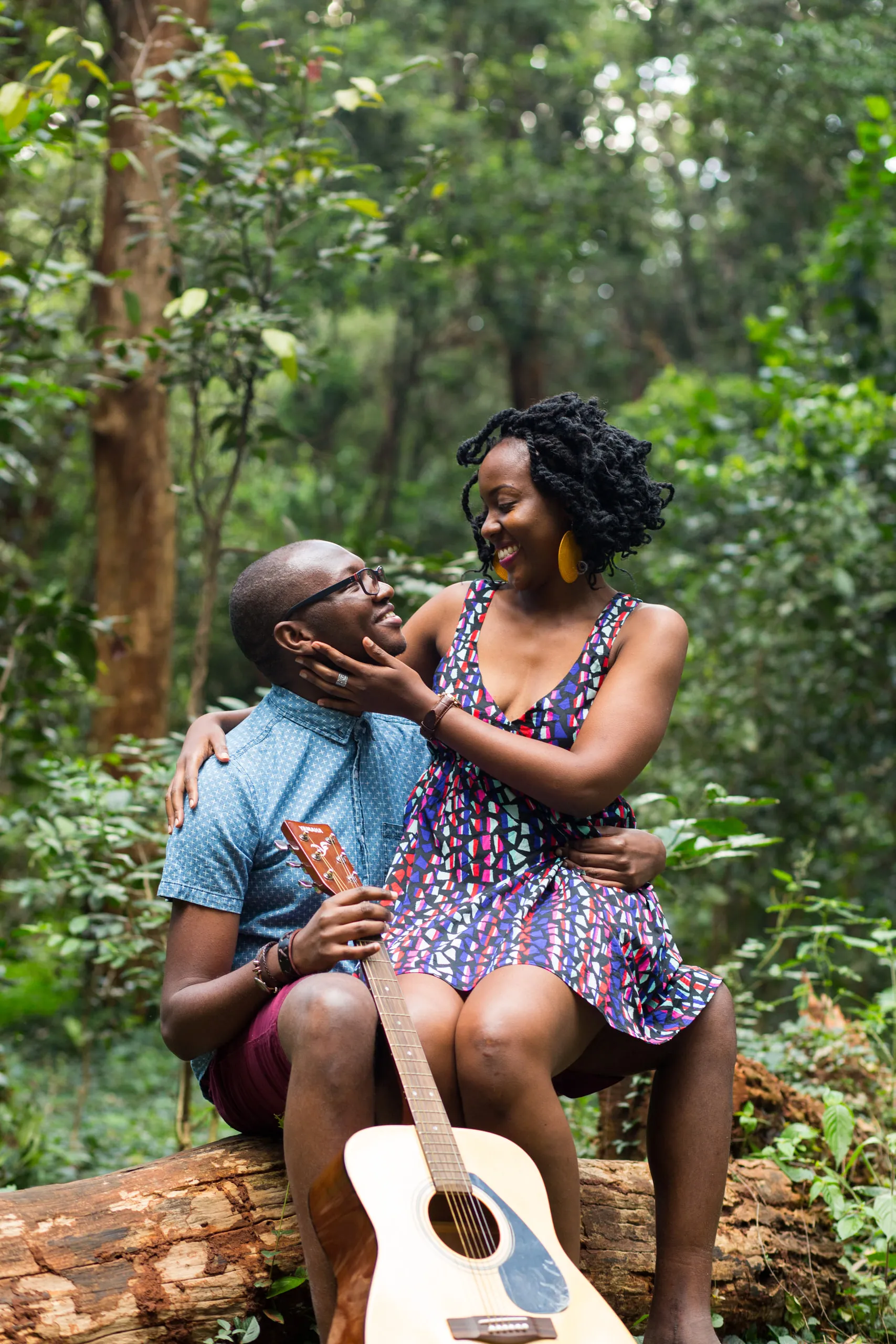 Couple on a log with a guitar, she touching his face
