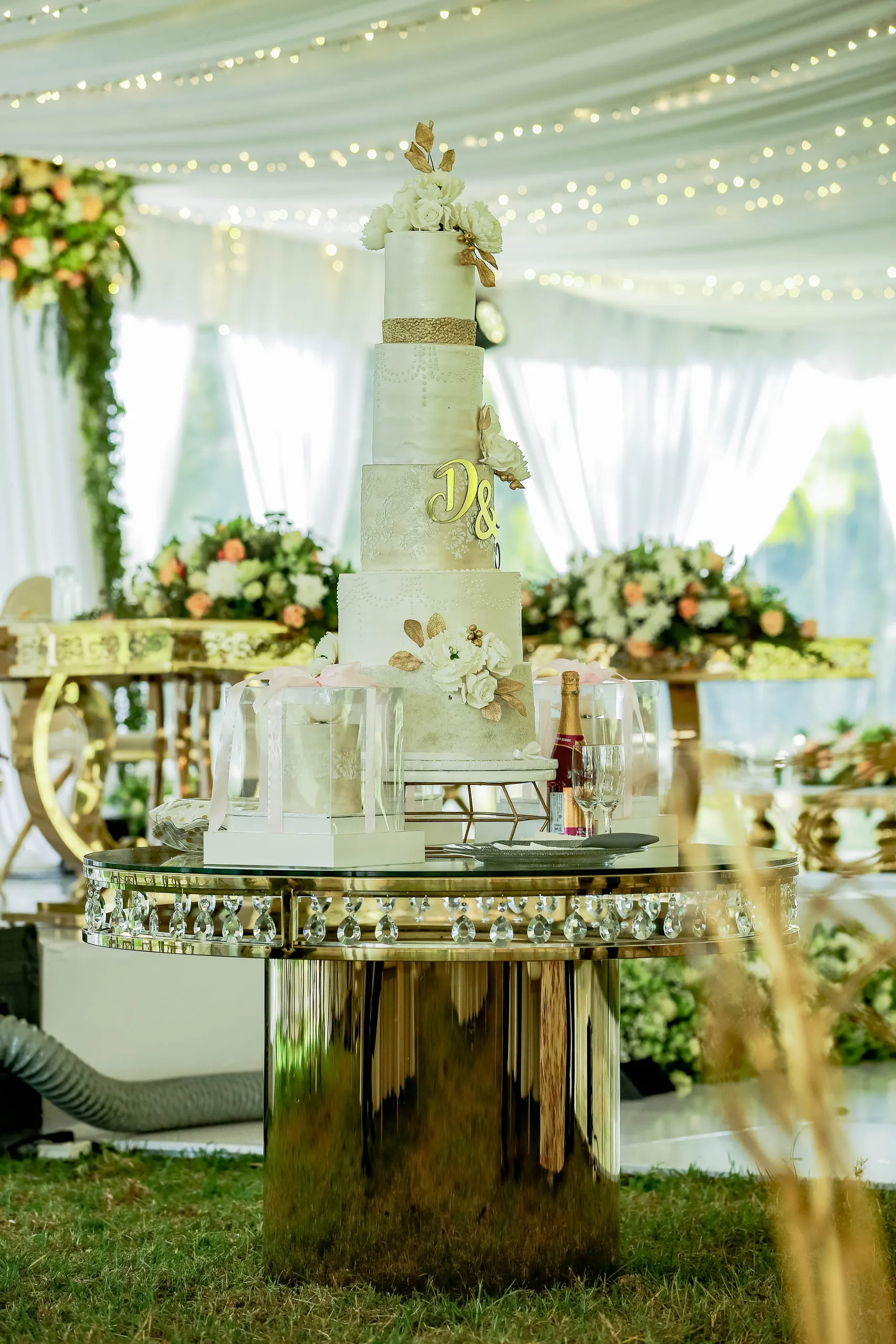 Tiered wedding cake on a mirrored table under warm lights