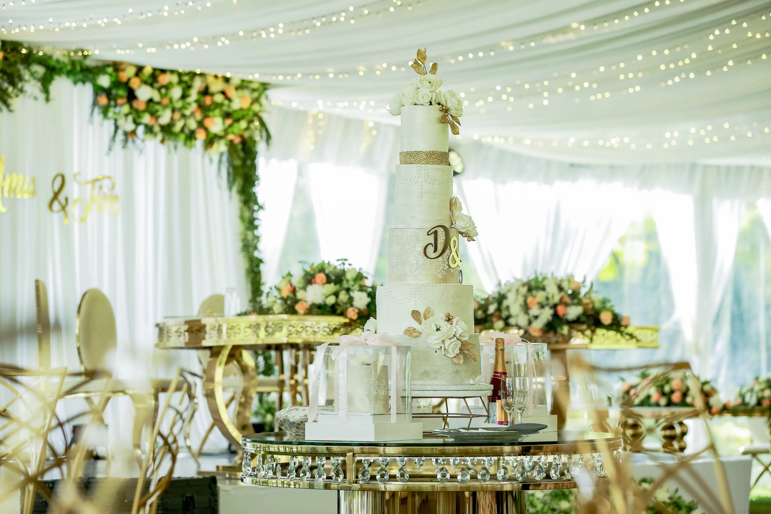 The wedding cake on a mirrored table under a tent of fairy lights