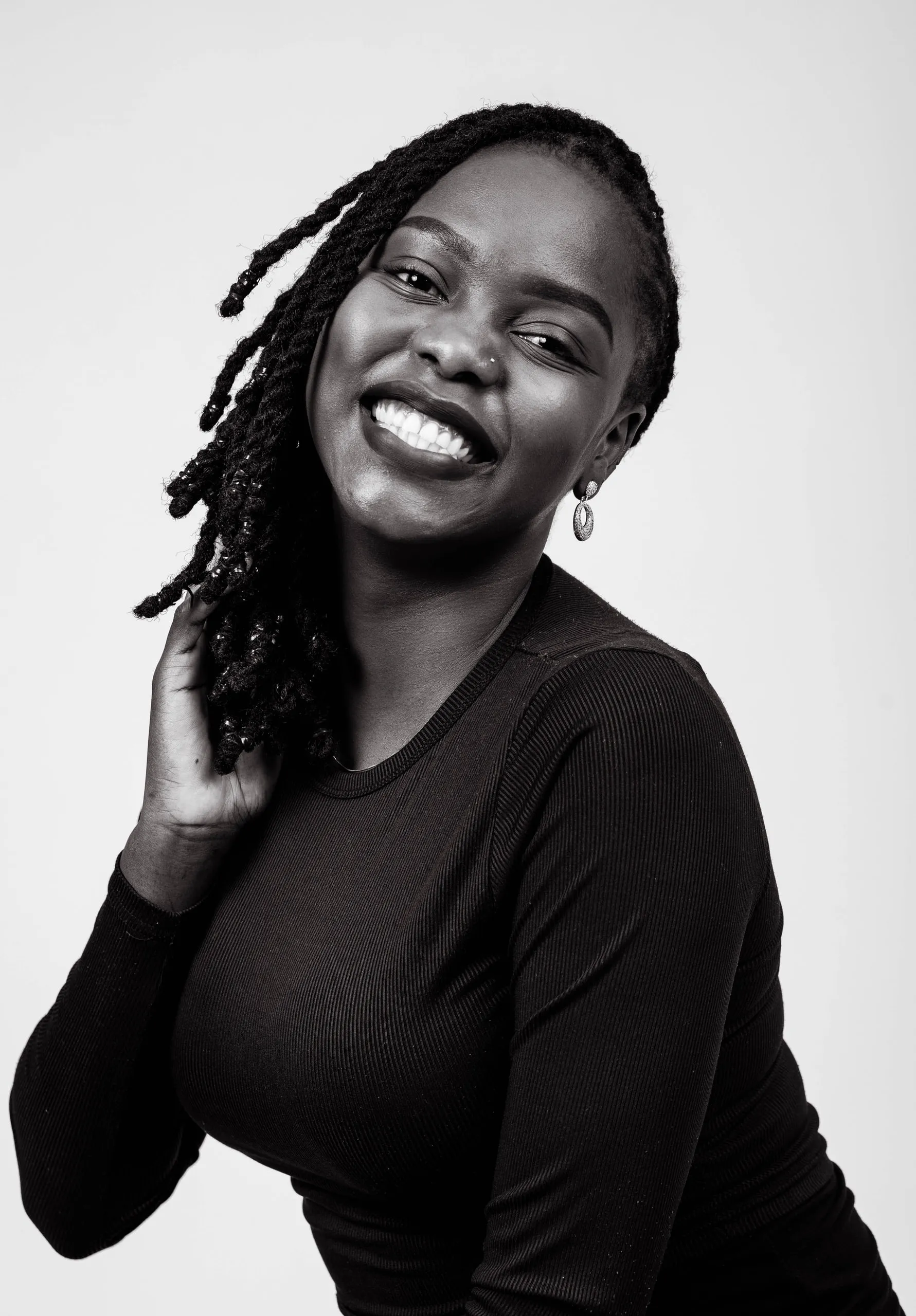 Woman with twisted locs laughing and tilting her head, in black and white