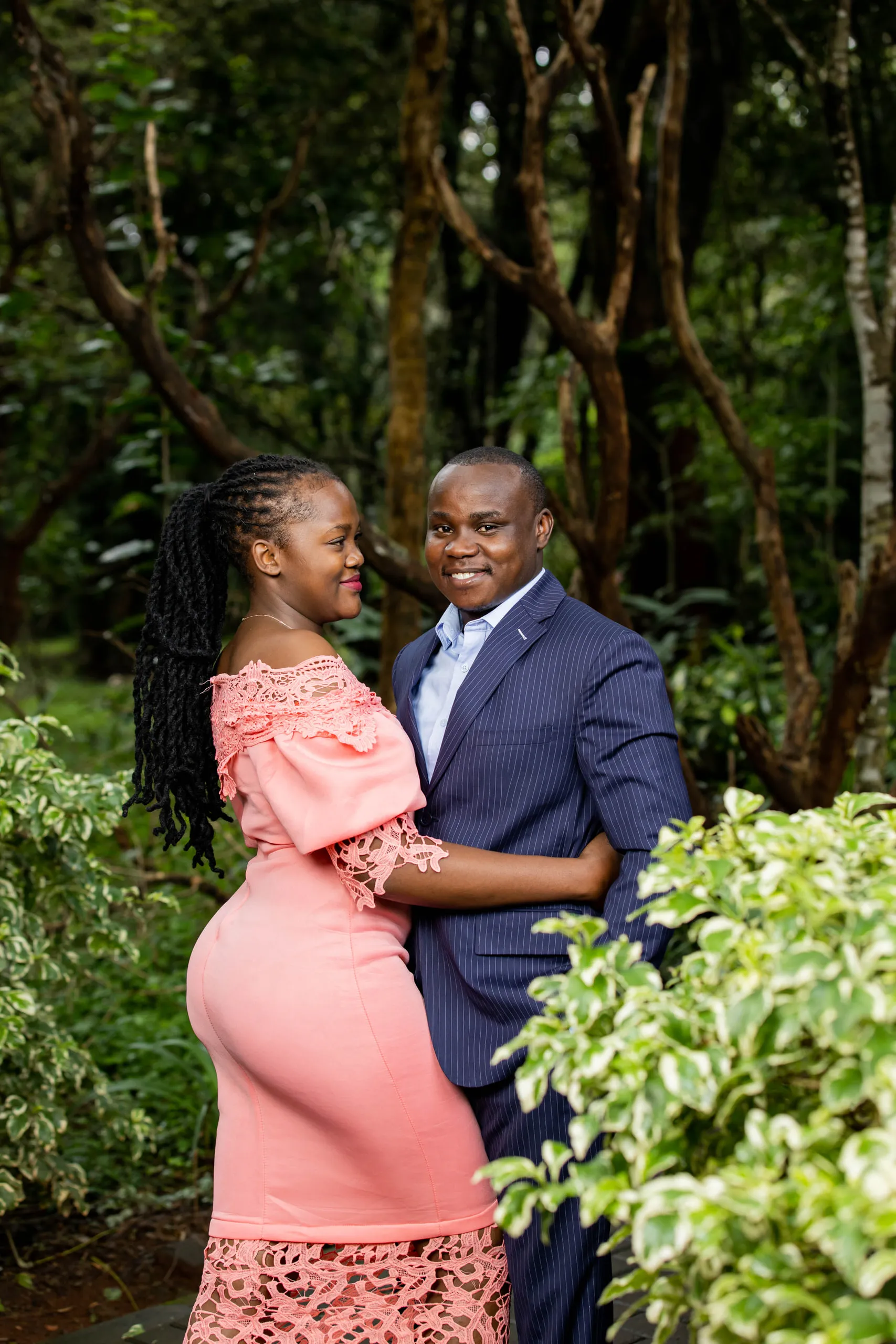 Couple embracing among leafy shrubs