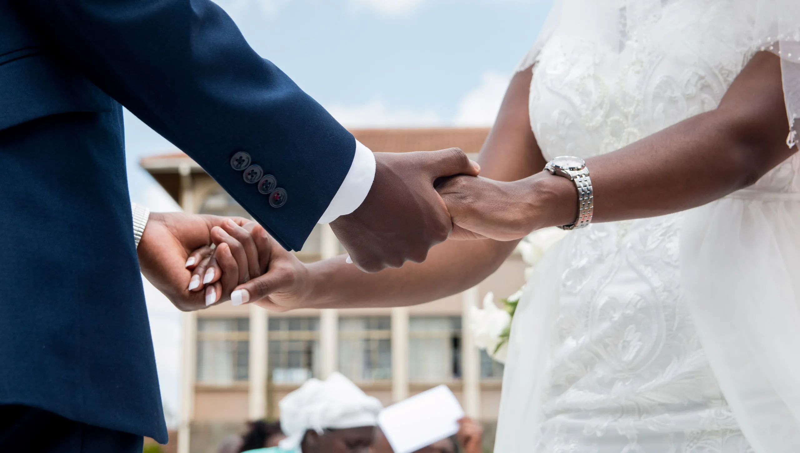 Close view of the bride and groom holding hands